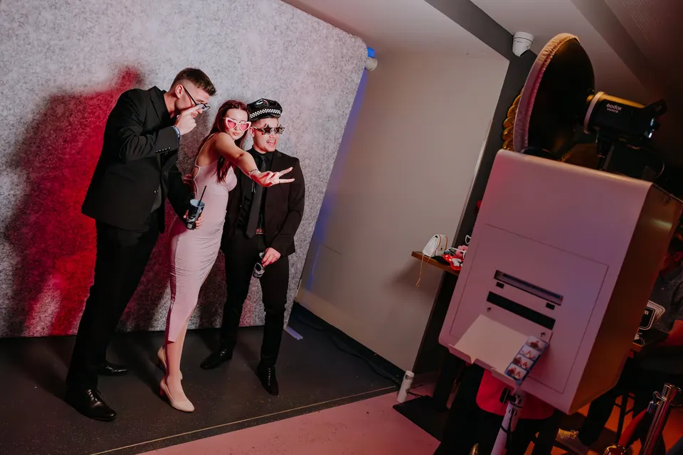 Vendégek pózolnak a selfie box előtt egy csillogó háttérnél